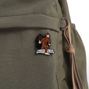 Nahaufnahme der Bigfoot-Emaille-Anstecknadel mit Spruch auf grünem Rucksack