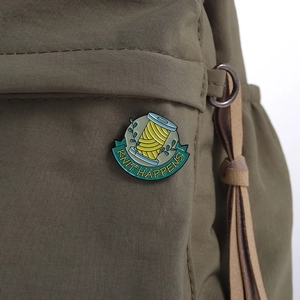 Nahaufnahme einer gelben Garnrollen-Emaille-Anstecknadel mit Knit Happens auf Canvas