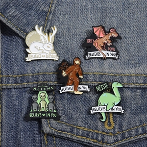 Close-up of five mythical creature enamel pins on denim jacket with motivational banners