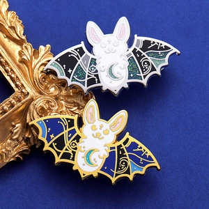 Detail view of dark punk bat rabbit enamel pins on premium blue velvet with gold frame