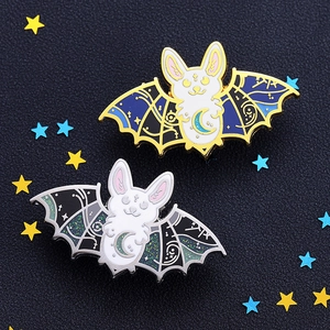 Detailed macro view of enamel bat cat pins with glitter stars on a textured background