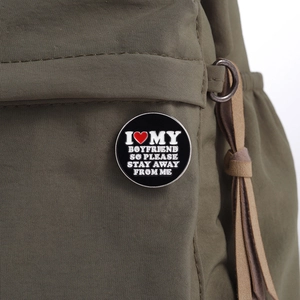 Detail of round black enamel pin on backpack with I Love My Boyfriend quote