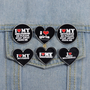 Set of 6 black enamel letter pins on denim jacket featuring heart and slogan designs