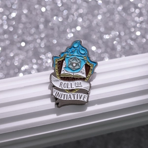 Épinglette émaillée de dé D20 avec flamme bleue sur socle blanc et fond scintillant