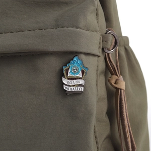 Détail du pin's émaillé dé d20 avec flammes bleues sur un sac à dos en toile vert olive