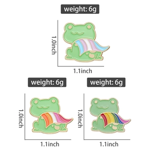Detail view of frog enamel pins with pride flags, showing dimensions 1.0 x 1.1 inches and weight 6g