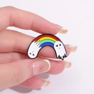 Rainbow ghost enamel pin in alloy metal being held against a neutral gray background