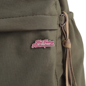 Dettaglio di una spilla smaltata rosa Not Today su tessuto di nylon verde militare