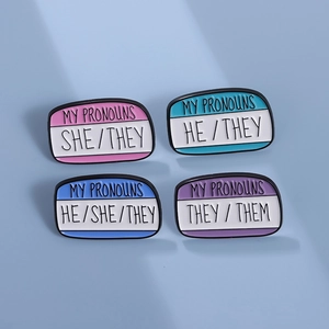 Set of four geometric enamel pronoun pins featuring SHE HE THEY markings in soft pastel colors