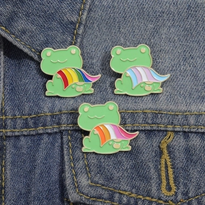 Detailed view of three cute frog enamel pins with LGBTQ+ pride flags on denim jacket