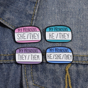Creative geometric enamel pins set with She/He/They pronoun labels on denim background