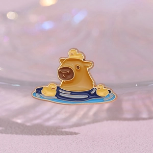 Cute capybara enamel pin with yellow ducks in blue water featuring gold metal edges