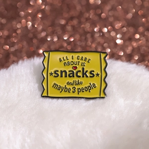 Gelbe Emaille-Brosche Snack-Tüte mit lustigem Spruch auf weißem Kunstpelz-Hintergrund