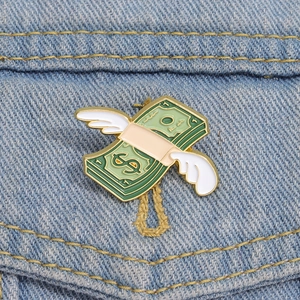 Dettaglio macro della spilla smaltata dollaro alato su tessuto denim blu scuro