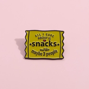Lustige gelbe Emaille-Anstecknadel in Snacktüten-Form auf rosa Hintergrund