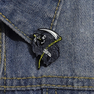 Detail of grim reaper enamel pin with scythe on blue denim jacket collar