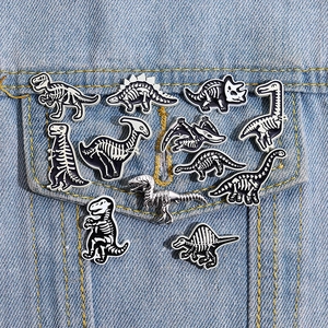 Set of 11 cartoon punk dinosaur skeleton enamel pins on a blue denim jacket pocket