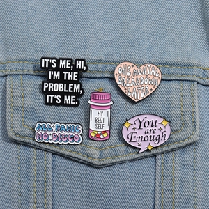 Close-up of colorful enamel letter brooches pinned to a light blue denim jacket pocket