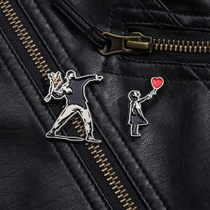 Close-up of Banksy-style Flower Thrower and Girl with Balloon enamel pins on a black leather jacket