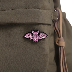 Nahaufnahme der rosa Fledermaus-Emaille-Anstecknadel auf grünem Rucksack