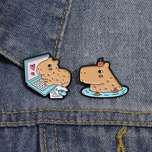 Creative capybara enamel pin set featuring orange bath and laptop designs on denim jacket