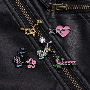 Detalle de cinco pines esmaltados de fórmulas químicas sobre una chaqueta de cuero negro