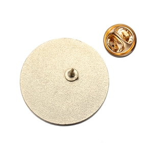 Detail of round gold enamel pin back featuring frosted metal texture and butterfly clasp