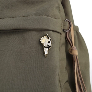 Detailed close-up of a snake and sun enamel brooch pinned on a green canvas bag