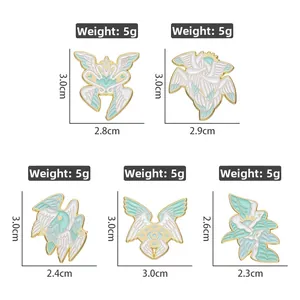 Detailed macro view of white and mint green wing-shaped enamel pins with gold accents
