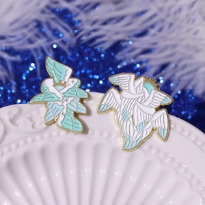 Cartoon winged eye enamel pins set in white and mint green with golden metal edges
