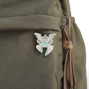 Detail of mint green wing enamel pin on a backpack showing real wearing effect