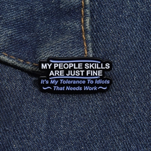 Close-up of enamel quote brooch pinned on denim jacket showing sarcastic text detail