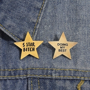 Close-up of star-shaped metal pins with text on denim jacket fabric
