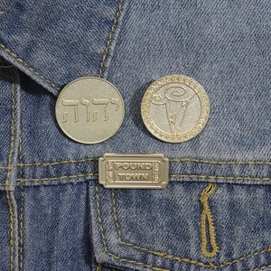 Vintage gold metal enamel pins set with Hebrew text and cloud icons on denim jacket