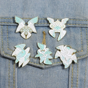 Detail of five wings and eye enamel pins on denim jacket with gold plating and white finish