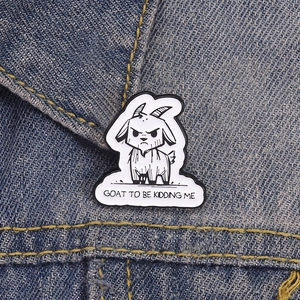 Funny cartoon goat enamel pin with GOAT TO BE KIDDING ME slogan on blue denim jacket