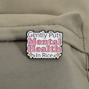 Detail of funny mental health enamel pin on a green canvas bag with stars
