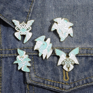 Set of 5 celestial enamel pins with white wings and eye icons on a denim jacket