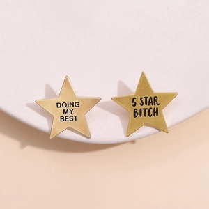 Golden five-pointed star metal badges with engraved slogans on a white platform