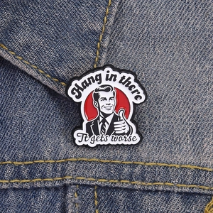 Dettaglio di una spilla smaltata vintage con slogan ironico su denim blu scuro