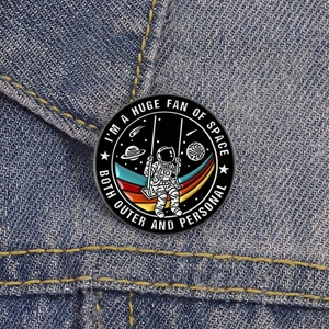 Cartoon-Emaille-Pin mit Astronaut auf Schaukel im Weltraum-Design auf Denim