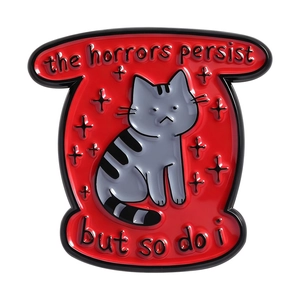 Spilla in smalto gatto grigio con testo the horrors persist but so do i su sfondo rosso