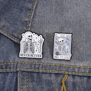 Skull enamel pin set with Never Better and Quiet slogans on blue denim background