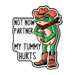 Funny green frog cowboy enamel pin with humorous 'Not Now Partner My Tummy Hurts' text