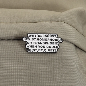 Macro view of enamel anti-discrimination pin on olive canvas with quote text details