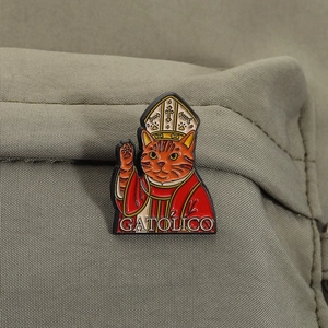 Detail einer lustigen Katzen-Bischof-Emaille-Anstecknadel auf olivgrünem Stoffhintergrund