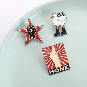 Funny goose and white duck enamel pins set with SLAY and HONK text on a ceramic tray
