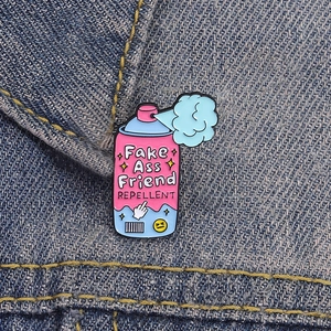 Pin's rigolo en émail rose forme spray Fake Ass Friend Repellent sur veste en jean