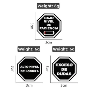 Detailed view of three 3x3cm black PVC badges with Spanish text and 6g weight spec