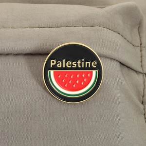 Dettaglio macro della spilla smaltata Palestina con motivo anguria su tessuto